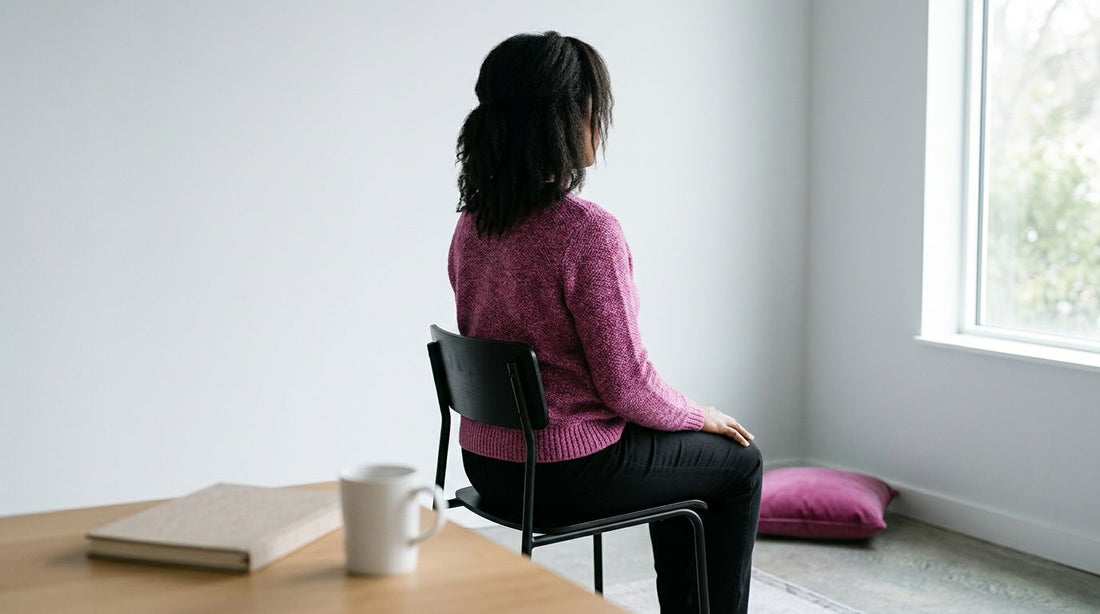 Mulher sentada em cadeira olhando pela janela