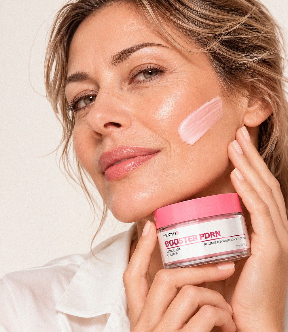 Mulher com o creme Booster PDRN no rosto, segurando o pote